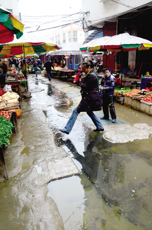 公平二街街尾,一抱着小孩的妇女猛地跨过"臭水沟".